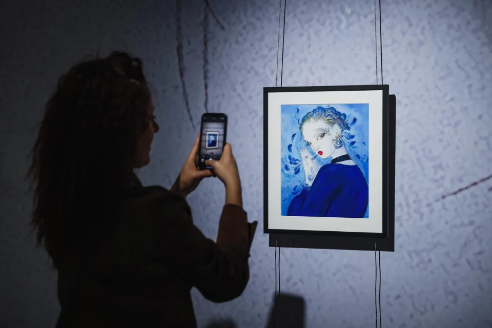 A visitor photographing one of Amano's large-format gallery paintings &mdash; the exhibition spaces artwork to encourage close viewing at human scale