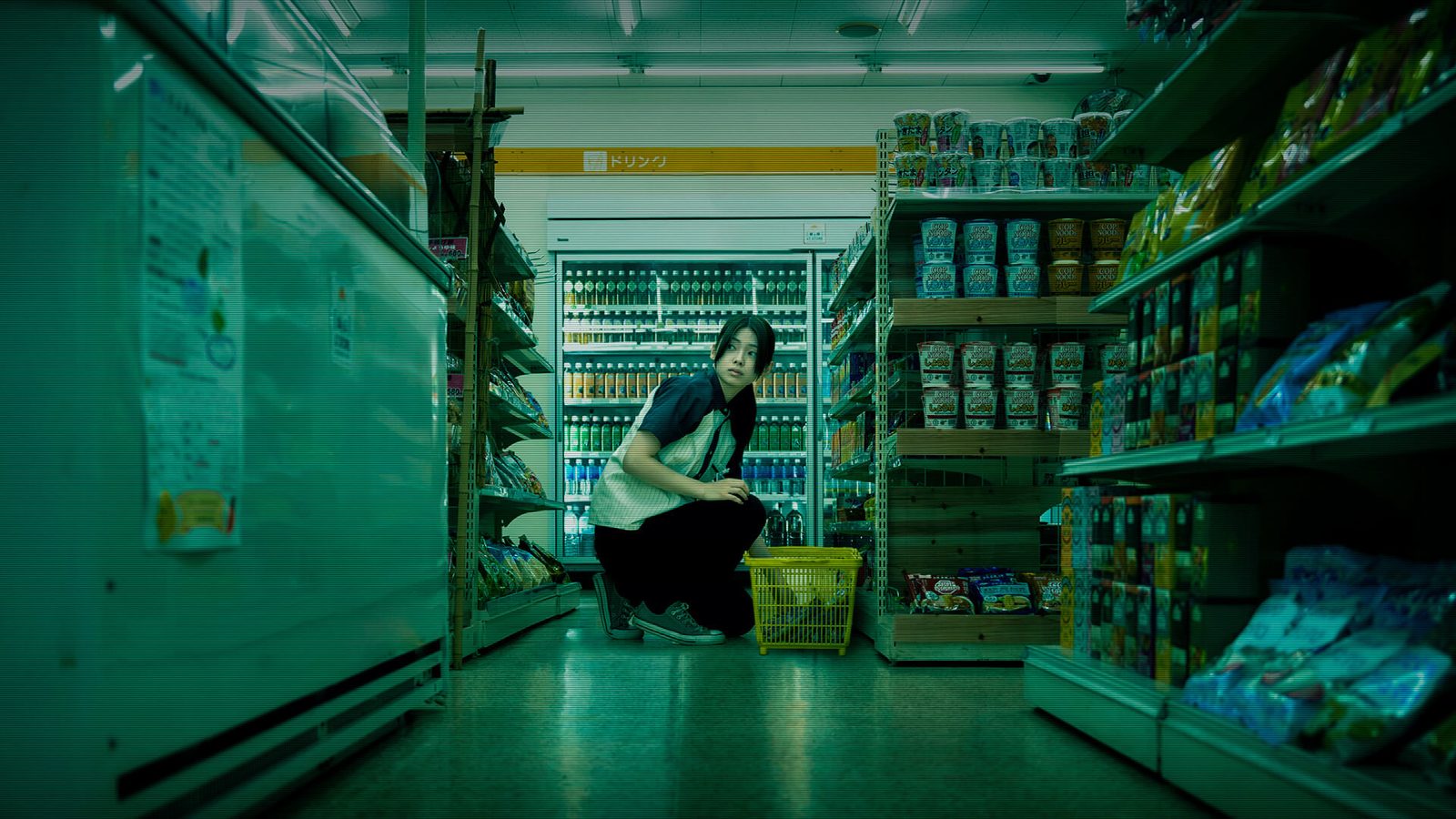 The Convenience Store film — a night-shift worker crouched between aisles. The same mundane-space-gone-wrong logic, translated from game to live-action