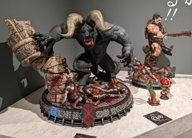 Nosferatu Zodd in human form and Guts &mdash; Prime 1 Studio statues on the Brand of Sacrifice base, visitors dwarfed by the scale