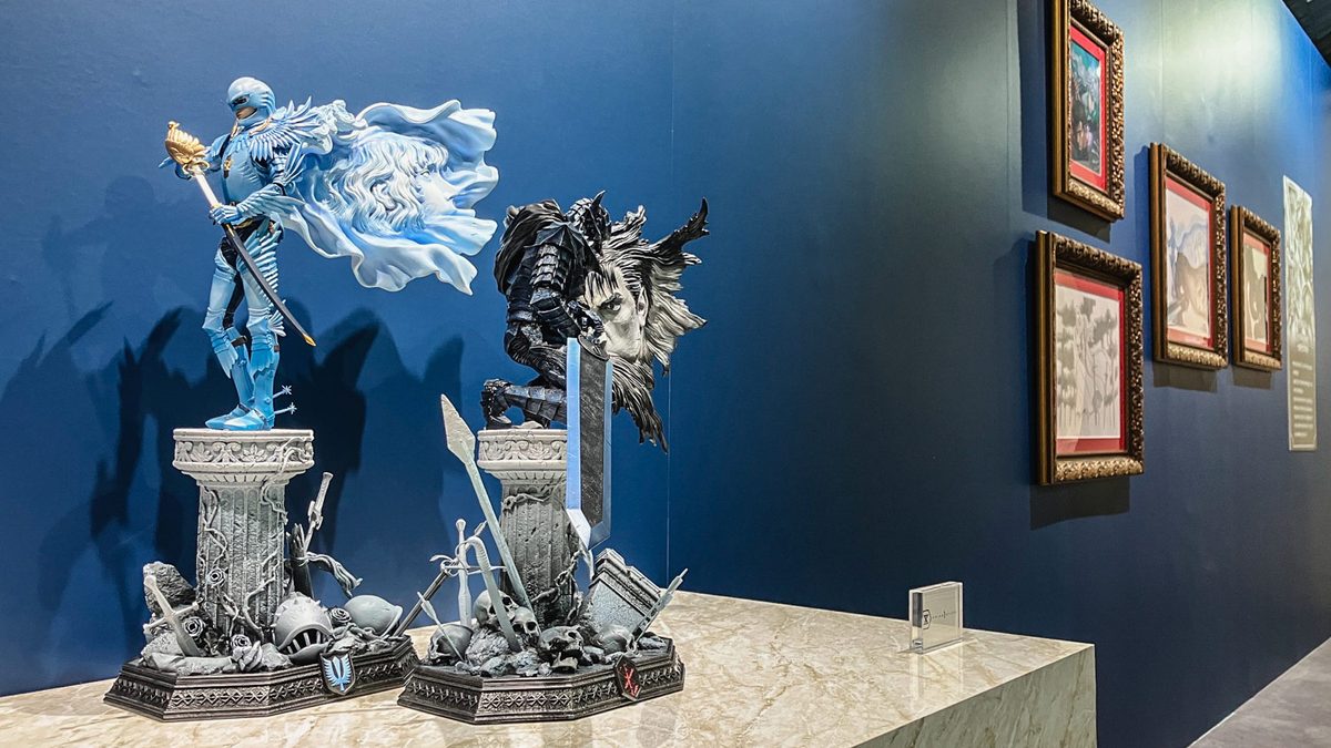 Griffith and Guts &mdash; paired Prime 1 Studio statues, the Hawk of Light in luminous blue alongside the Berserker in black, with Miura's framed color artwork behind