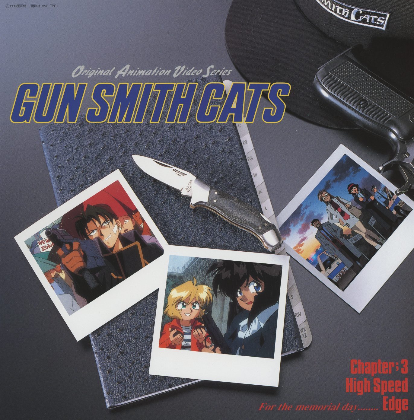 Vol. 3 booklet opening — 'For the memorial day... Edge.' Photograph of physical props: a branded folding knife, a Gun Smith Cats cap, a notebook, and polaroid snapshots from Episode 3. Still-life photography, not illustration.