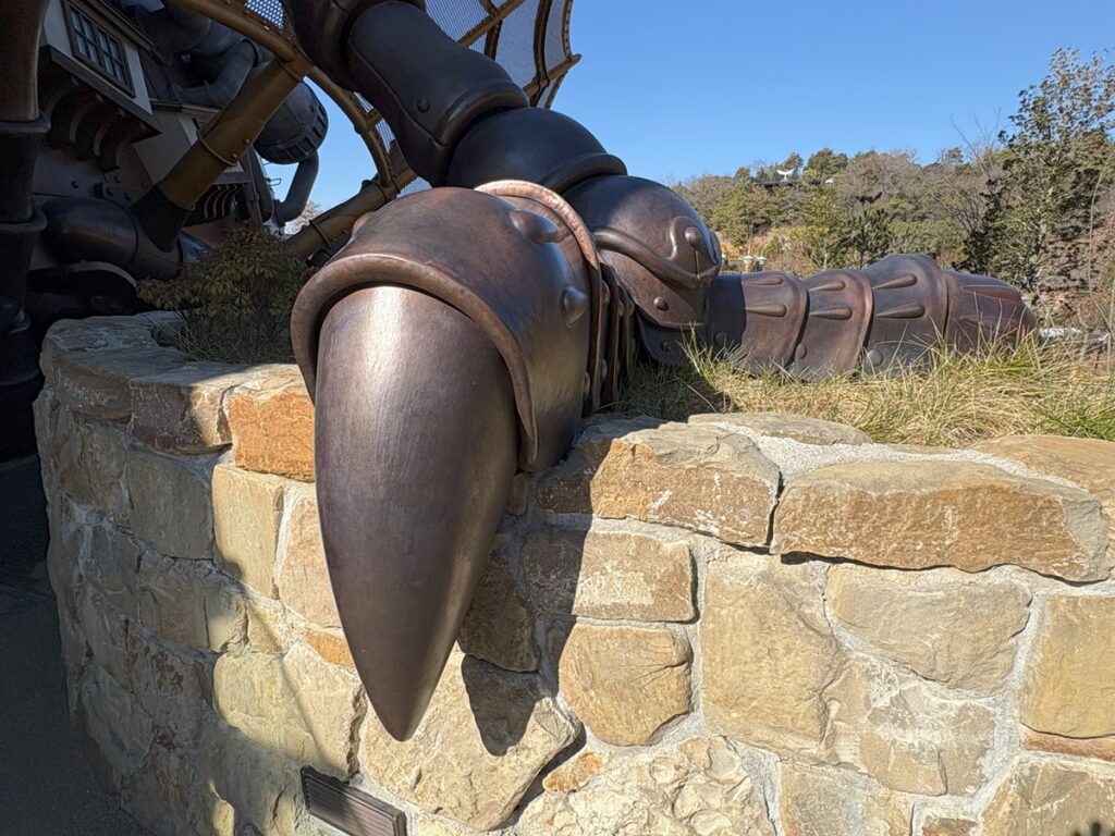 Copper leg detail &mdash; the mechanical claw resting on stone masonry, showing the real metal and traditional setting techniques up close