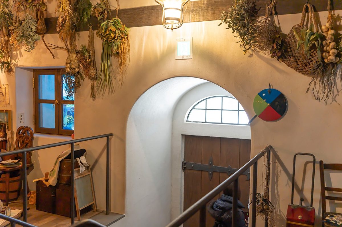 The rotating four-color door dial &mdash; the mechanism from the film that changes which world the door opens onto, mounted beside an arched doorway with dried herbs above