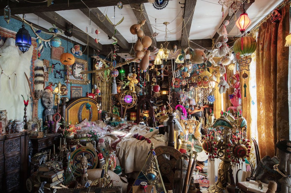 Howl's bedroom &mdash; the wizard's personal space, cluttered ceiling-to-floor with trinkets, instruments, masks, and curiosities hanging from timber beams