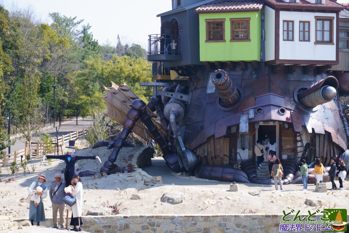 The castle from below &mdash; Turnip-Head scarecrow at left, mechanical wing structure, visitors entering beneath the copper legs