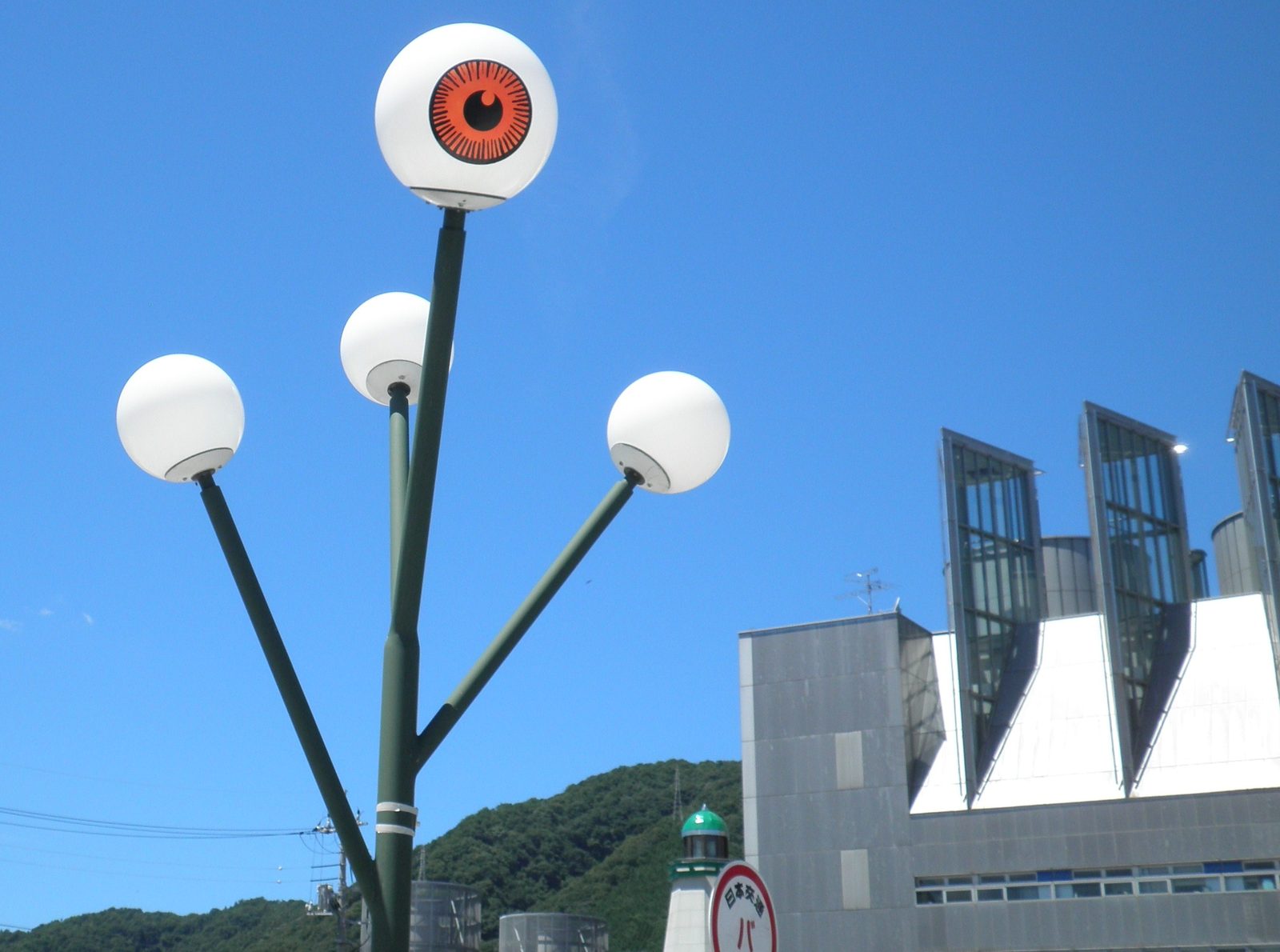 Sakaiminato — Medama-oyaji street lamps outside the Mizuki Shigeru Museum. A town of 33,000 that turned one man's folklore drawings into civic infrastructure. The eyeball watches the bus stop