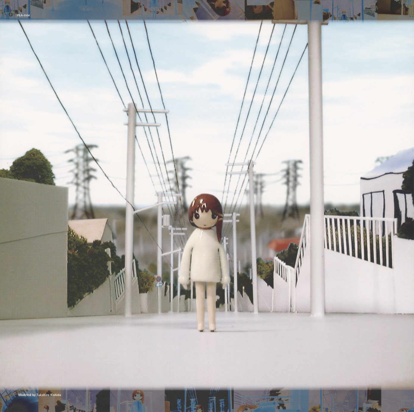 lif:04 gatefold interior. A three-dimensional miniature diorama — small Lain figure standing on a model suburban street with real wire power lines, buildings constructed from printed paper and cut materials. The anime reconstructed as physical sculpture. Photographed in real light. Credit: Takahiro Kishida.