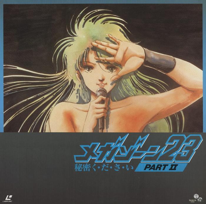 Disc 2 front jacket — メガゾーン23秘密ください PART II. Same Eve image and pose as Disc 1, but with a blue metallic lower band replacing the dark ground. The subtitle 秘密ください ("please keep it secret") runs beneath the PART II designation. taxco logo lower right.
