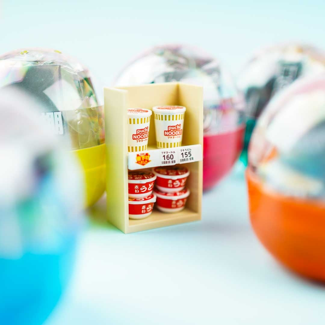 Kenelephant miniature convenience store shelf — the onigiri have printed labels, the drink bottles have brand-accurate caps. 1/12 scale retail archaeology