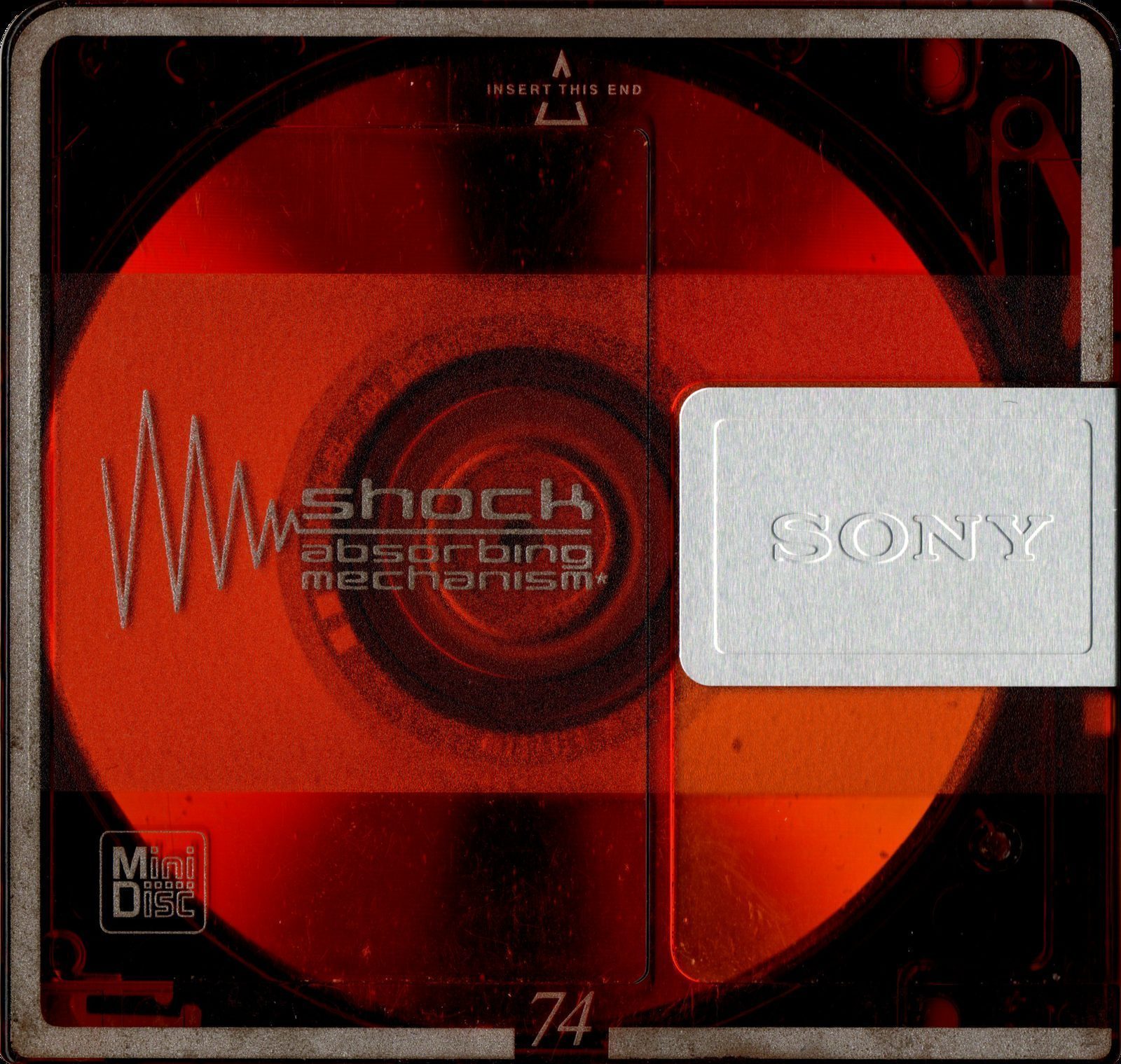 Sony 74-minute MiniDisc — the red optical disc visible through the transparent cartridge shell. 'Shock absorbing mechanism' printed on the case. Still manufactured, still used