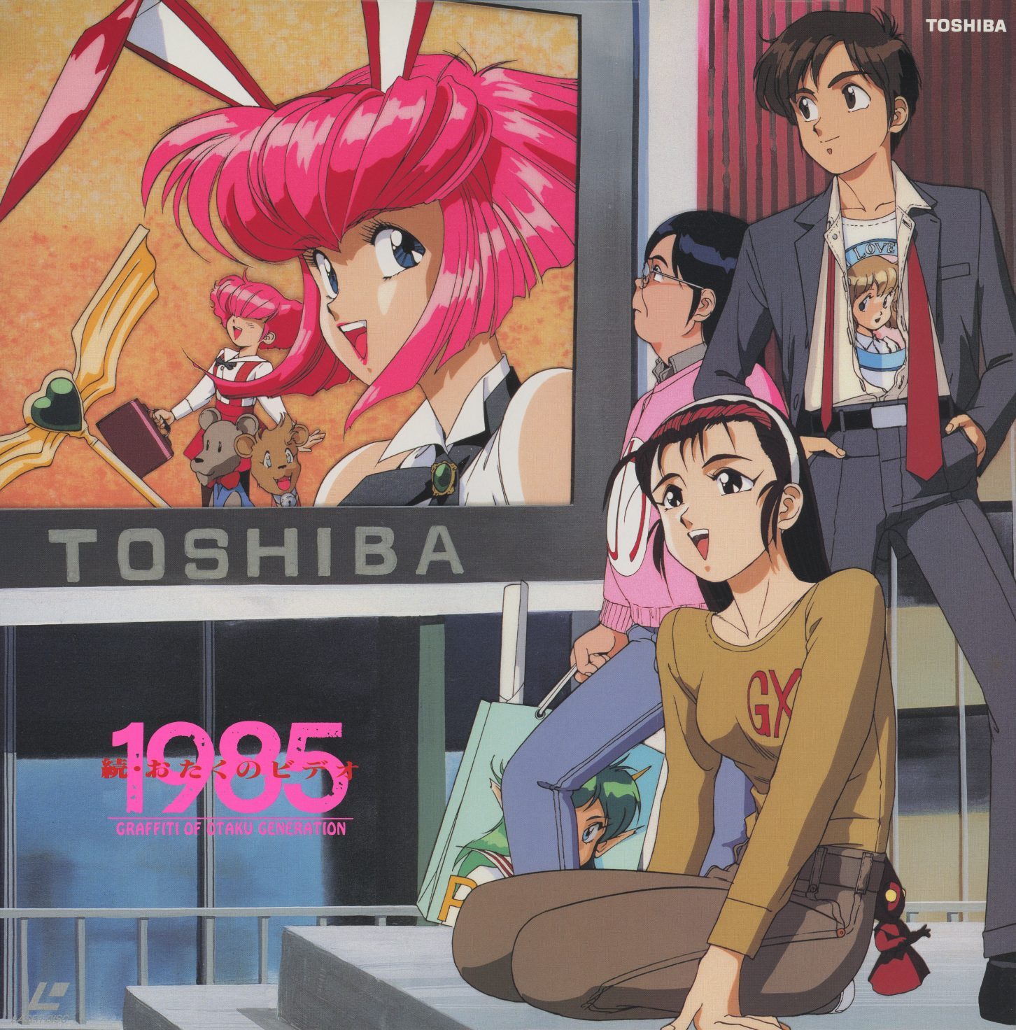 続・おたくのビデオ 1985 jacket front. Sonoda illustration — the characters three years older, now in Akihabara under a Toshiba billboard broadcasting anime. A girl in a 'GX' sweater in the foreground. The subculture has become a commercial landscape.