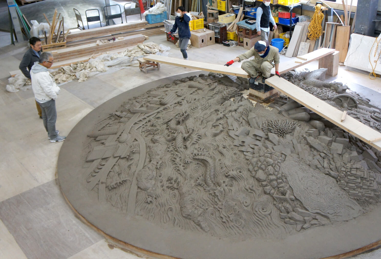 The full-size clay master on the CREARE studio floor &mdash; artisans sculpting the 5-meter disc by hand