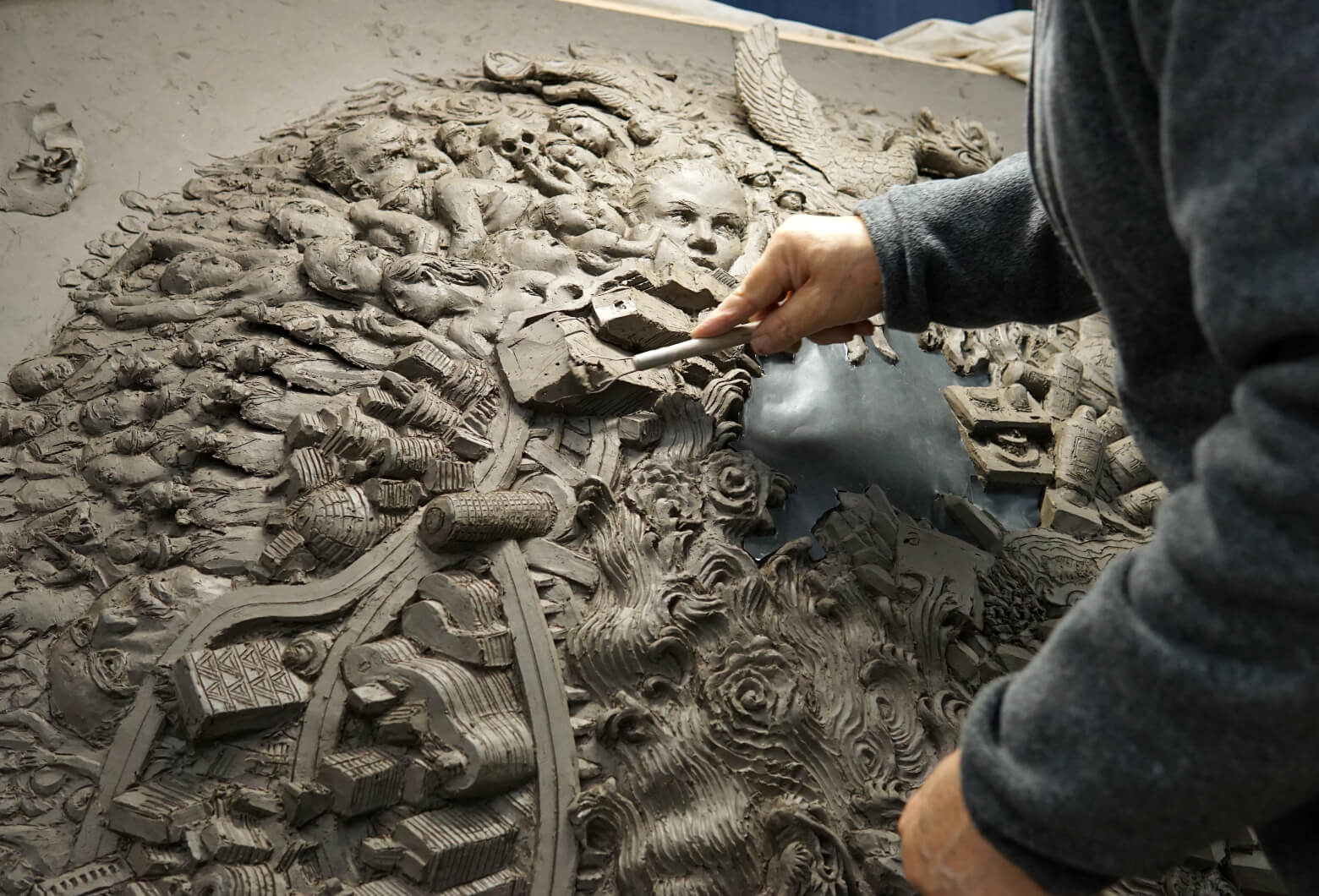 Hand-sculpting detail &mdash; building up the relief surface on the clay master