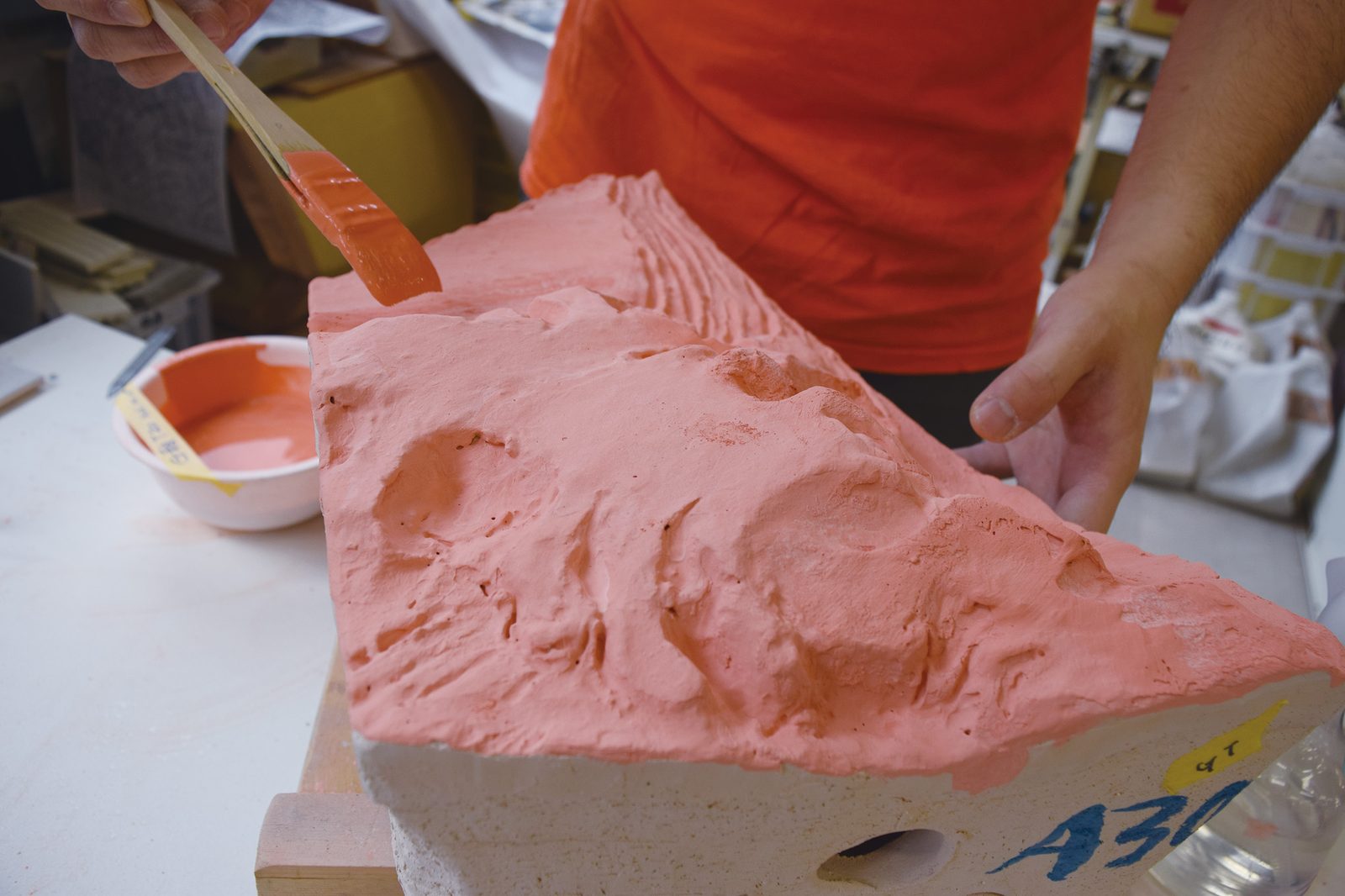 Hand-applying colored glaze to a wave section &mdash; tile A30 labeled for assembly