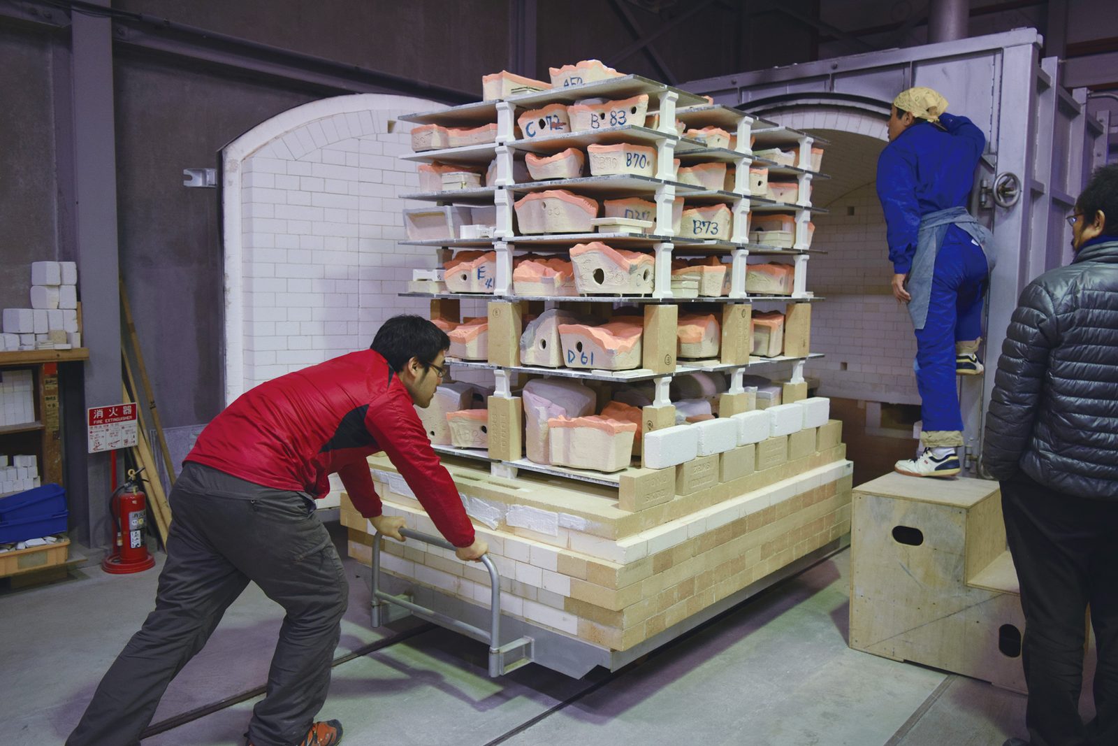 Loading glazed tiles into the kiln &mdash; each piece labeled by grid position
