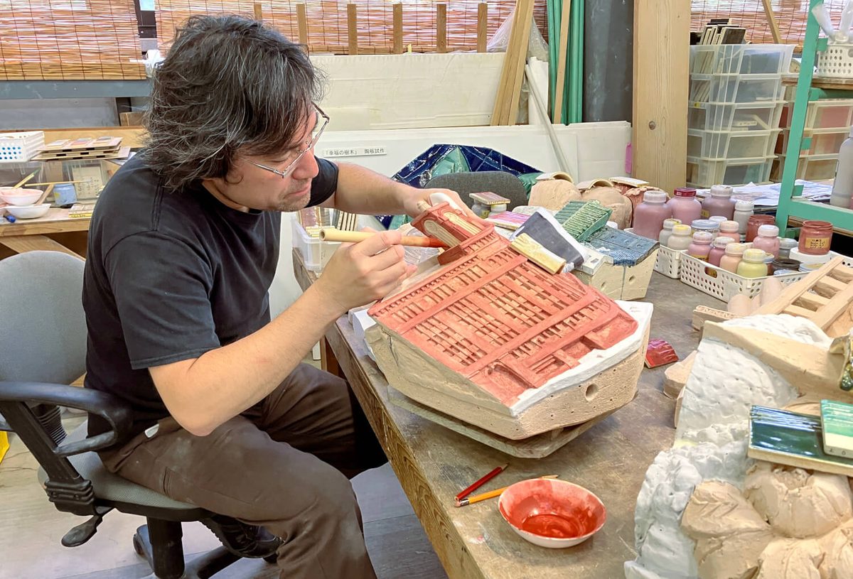 Hand-applying colored glaze to a building tile