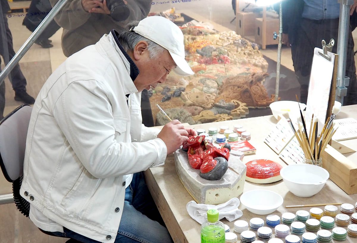 Otomo hand-painting Kaneda's motorcycle onto the ceramic at the December unveiling